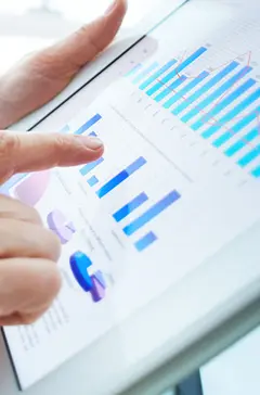 image: a hand using a tablet with multiple different graphs on it