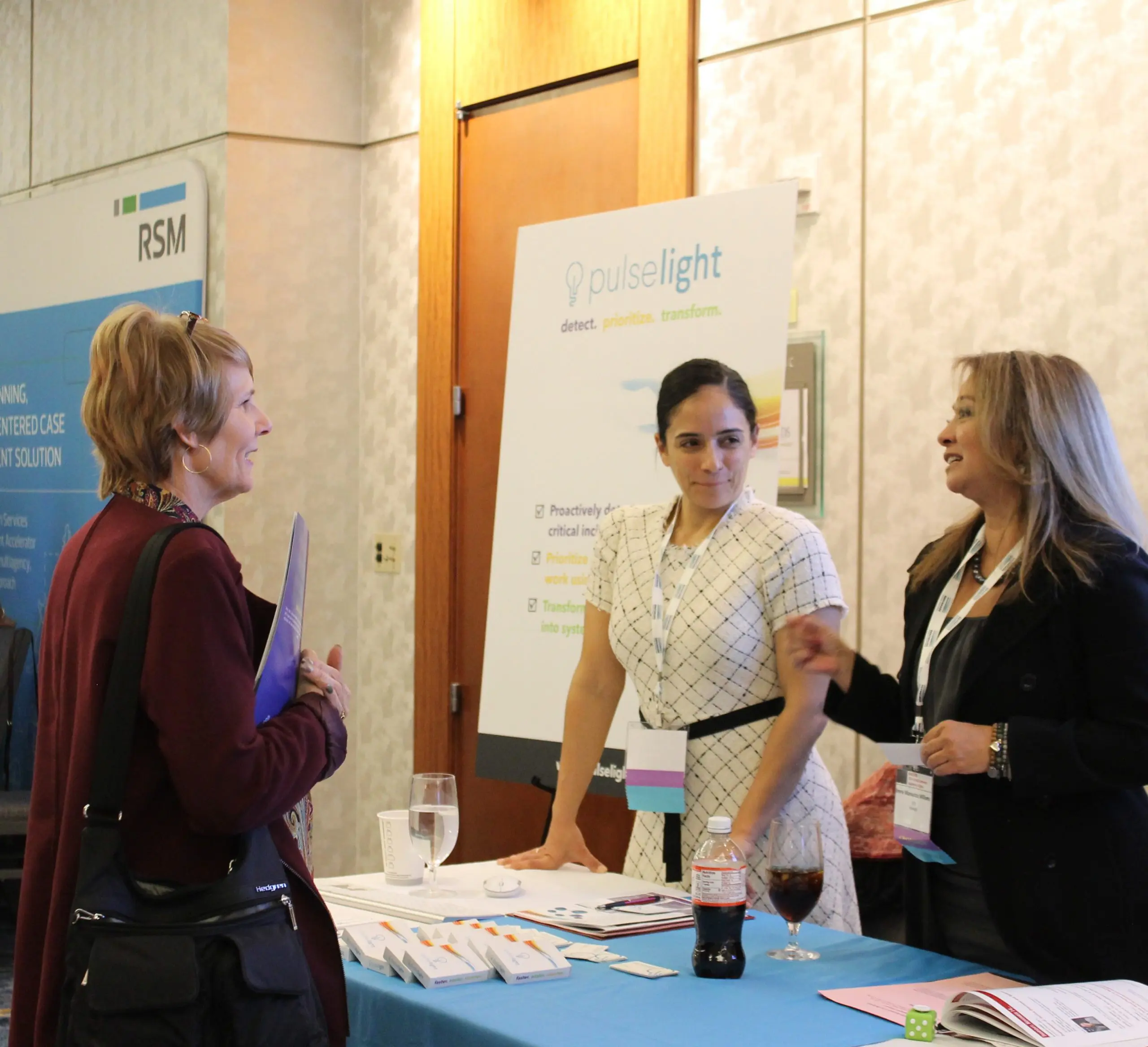 image: three women in business attire for the Pulselight table in a conference setting