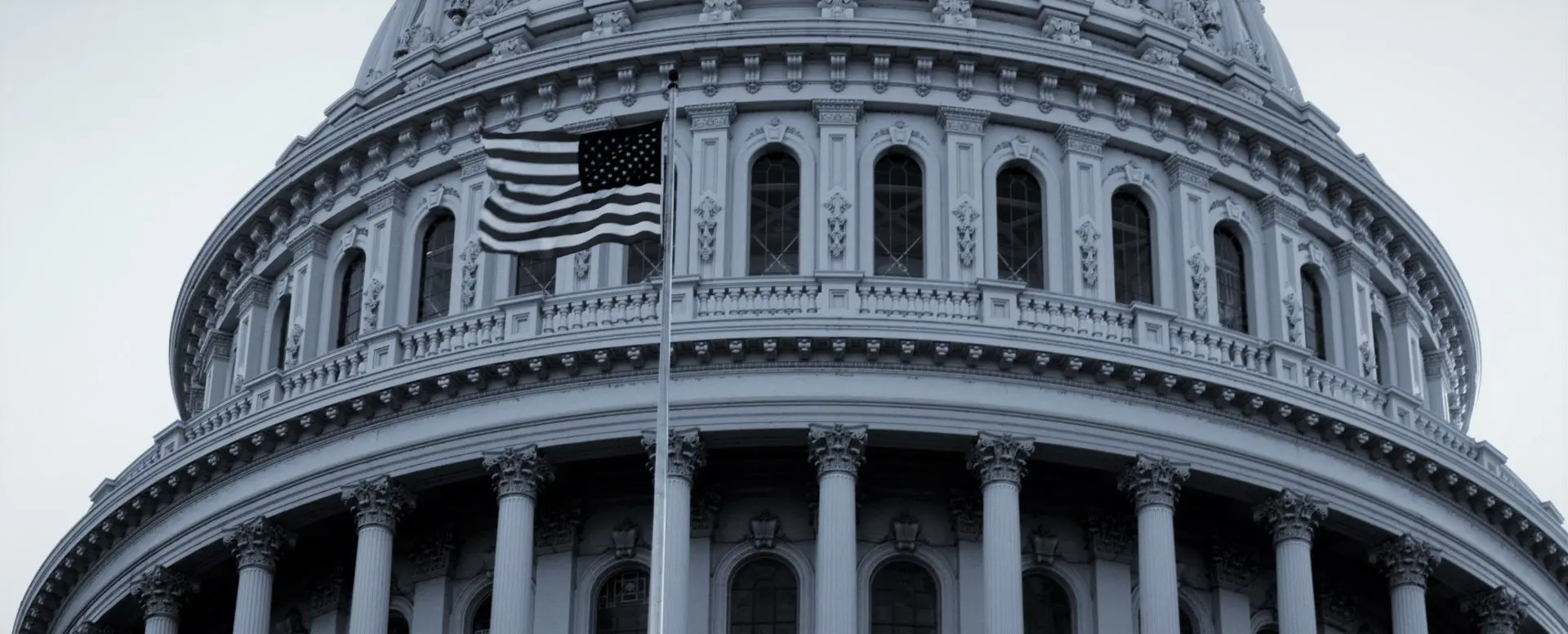 image: a black and white image of the capitol building with an american flag in the front