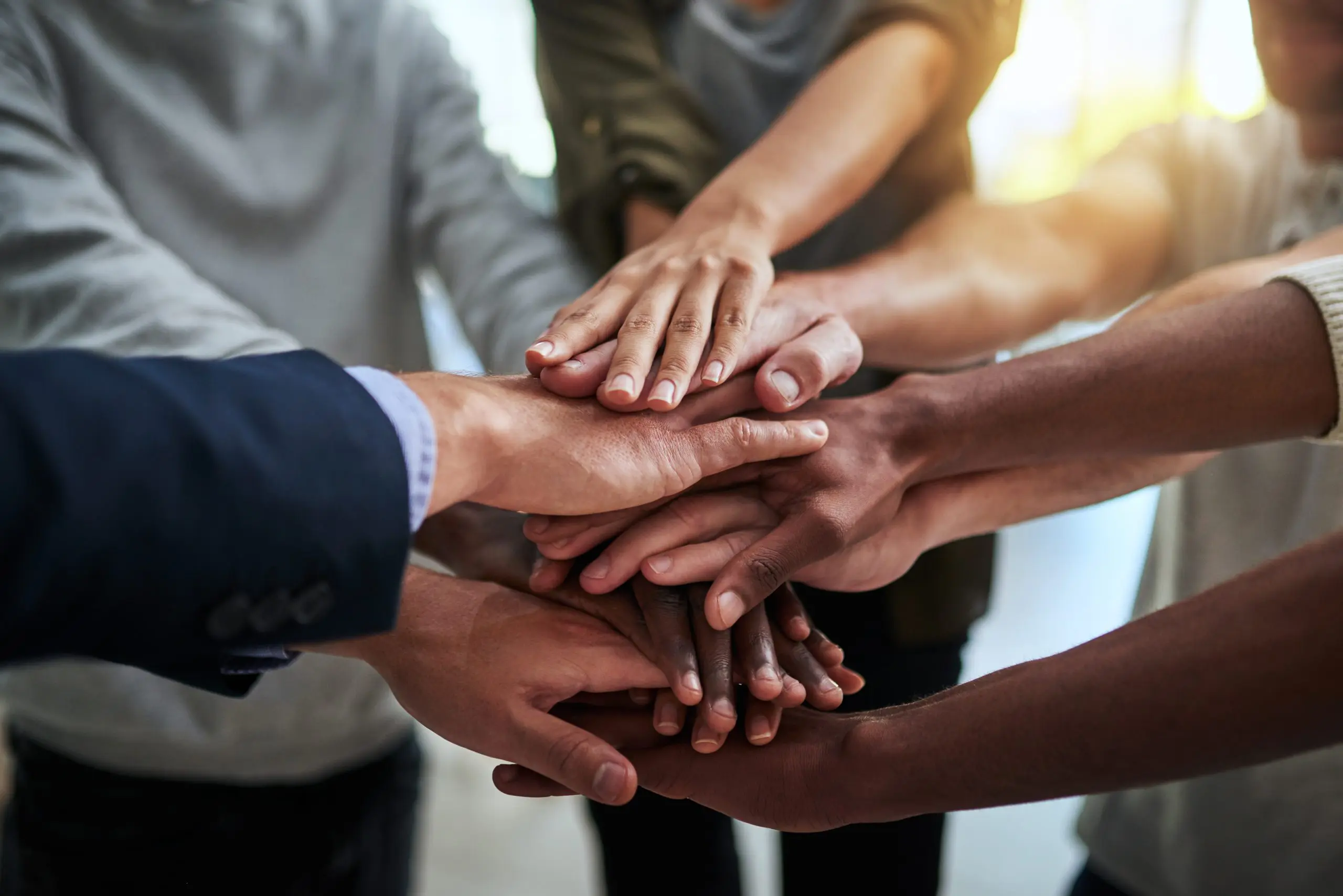 image: a group of hands joined in the middle of a circle of people