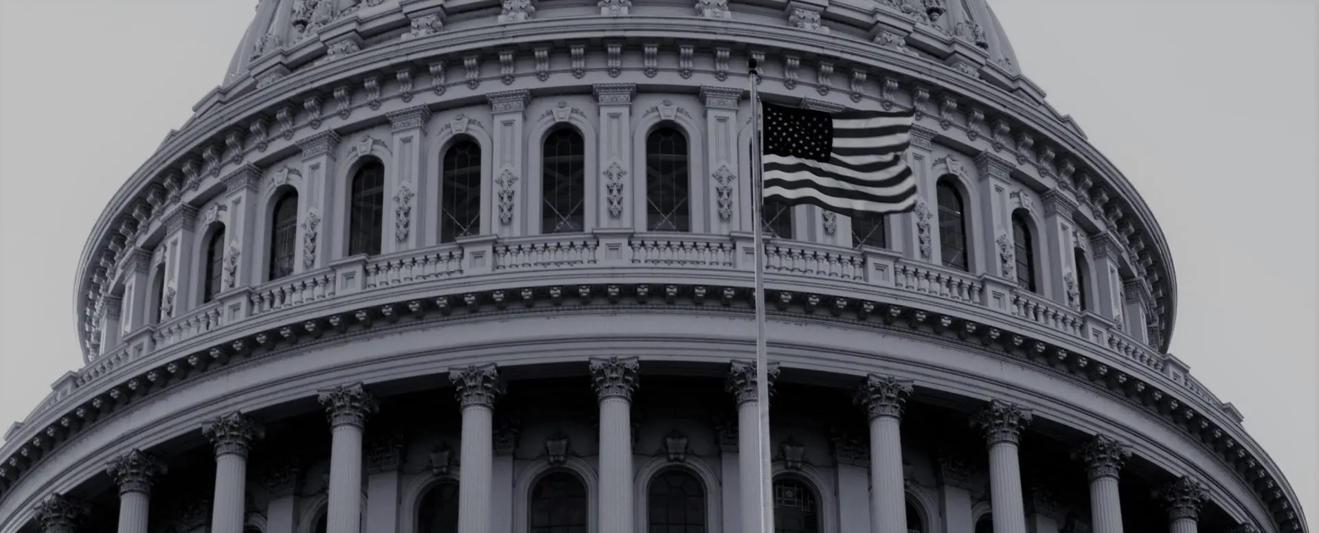 image: a black and white image of the capitol building with an american flag in the front